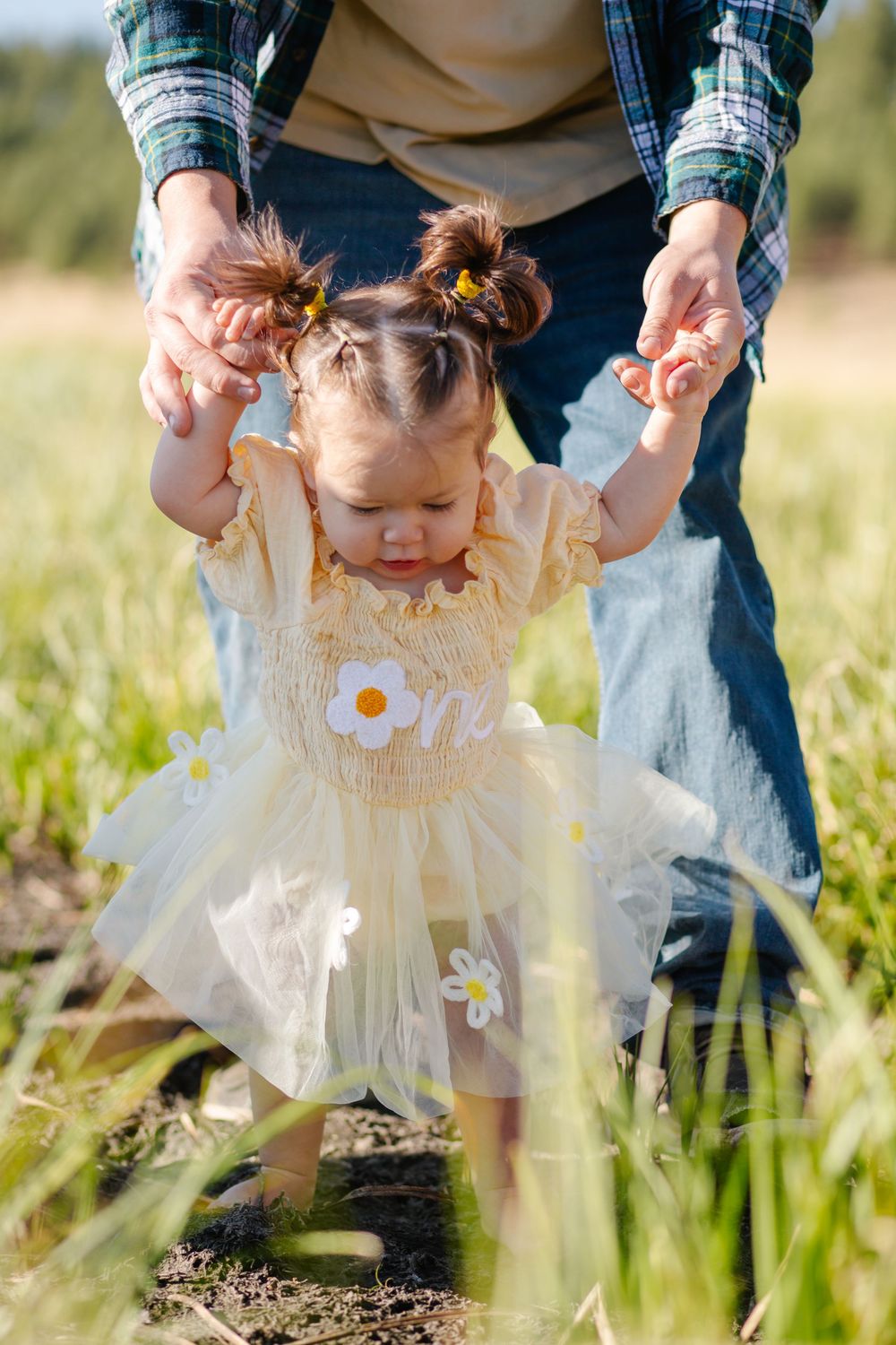 Small child in white dress plays in wildflower meadow during spring.