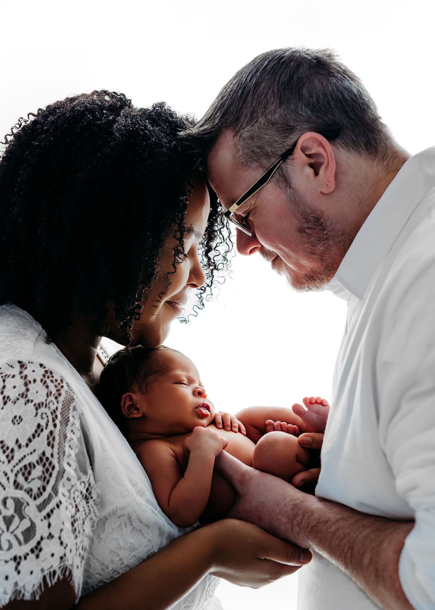 Parents tenderly gaze at their newborn baby in a touching intimate family moment.