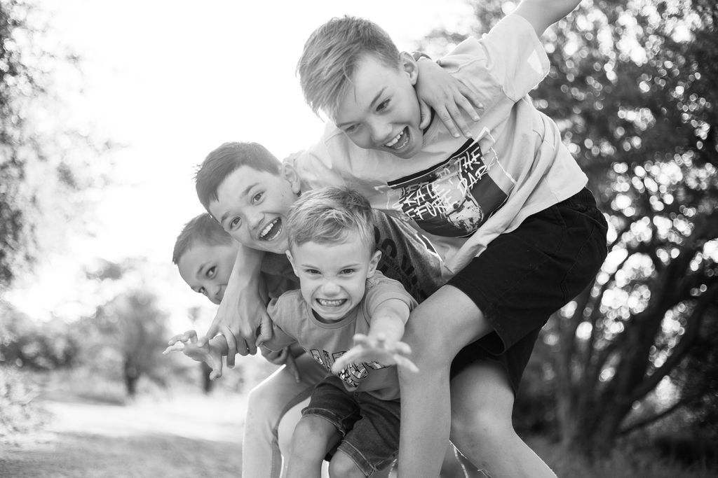 A playful black and white photo showing pure joy and laughter in natural outdoor setting.