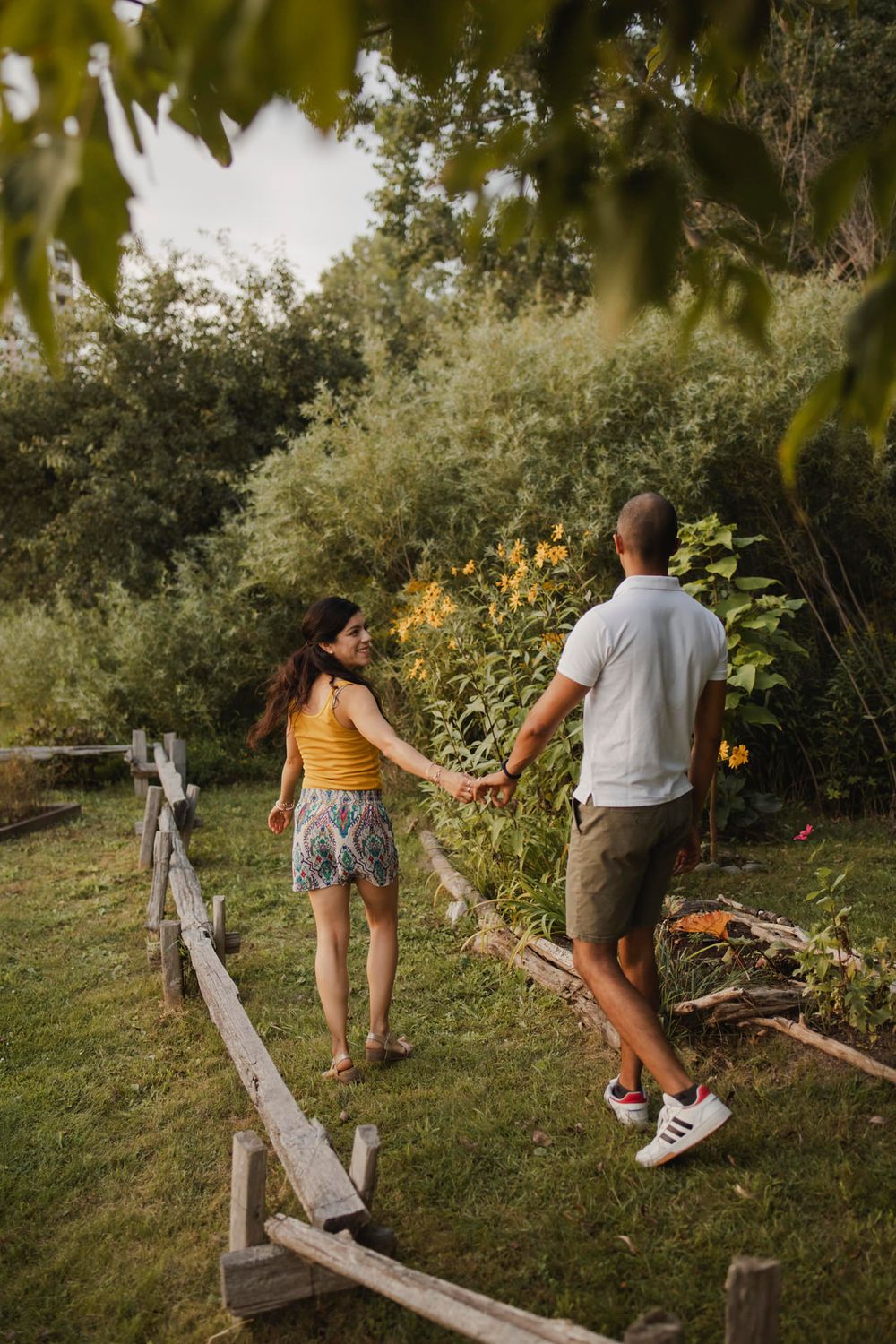 Couple walking among perennial  garden flowers at Lake Ontario, Kingston, ON, Ca. He kisses her hand.