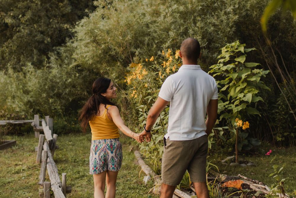 Couple walking among perennial  garden flowers at Lake Ontario, Kingston, ON, Ca. He kisses her hand.