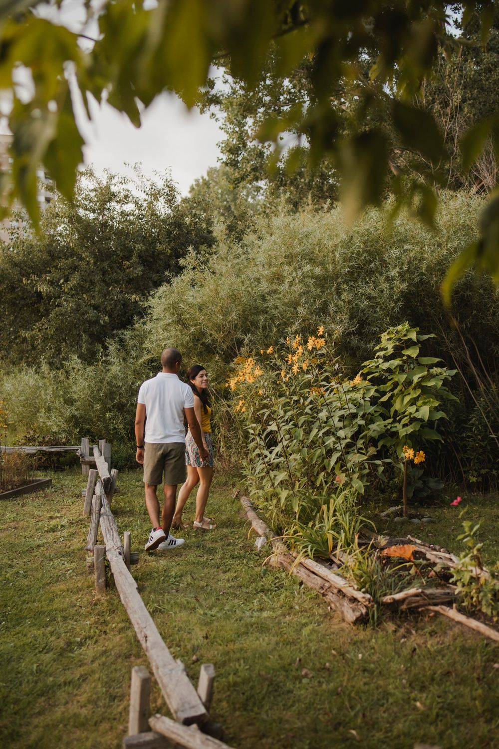 Couple walking among perennial  garden flowers at Lake Ontario, Kingston, ON, Ca. He kisses her hand.