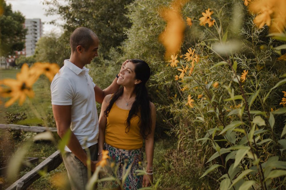 Couple walking among perennial  garden flowers at Lake Ontario, Kingston, ON, Ca. He kisses her hand.