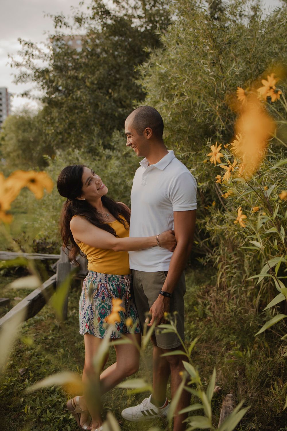 Couple walking among perennial  garden flowers at Lake Ontario, Kingston, ON, Ca. He kisses her hand.
