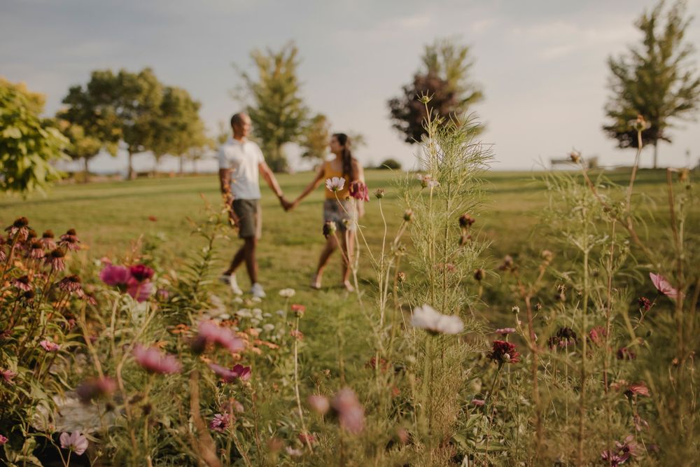 Couple walking among perennial  garden flowers at Lake Ontario, Kingston, ON, Ca. He kisses her hand.