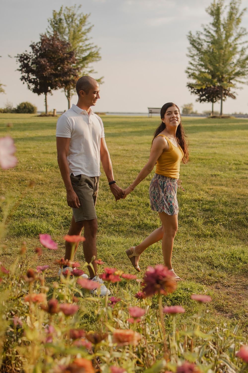 Couple walking among perennial  garden flowers at Lake Ontario, Kingston, ON, Ca. He kisses her hand.