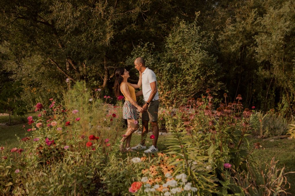Couple walking among perennial  garden flowers at Lake Ontario, Kingston, ON, Ca. He kisses her hand.