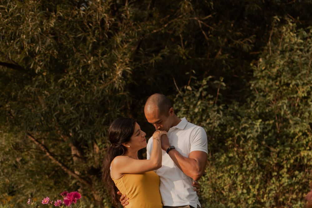 Couple walking among perennial  garden flowers at Lake Ontario, Kingston, ON, Ca. He kisses her hand.