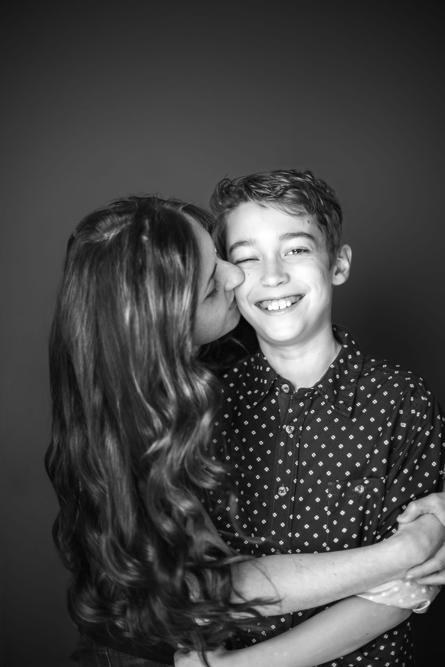 An intimate monochrome moment captured as a parent gives their child a loving kiss on the cheek.