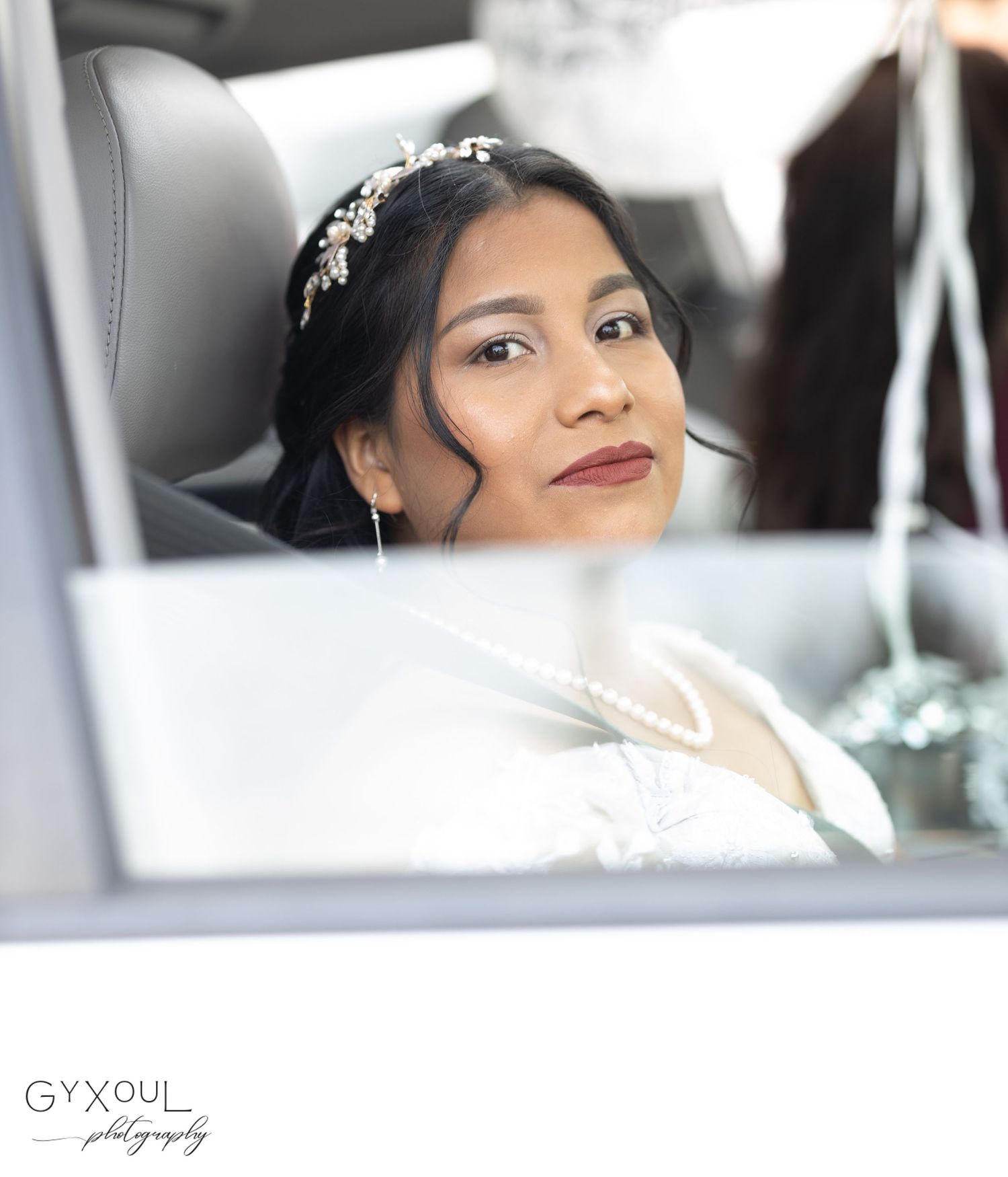 Elegant bridal portrait through car window showing crystal hair accessory.