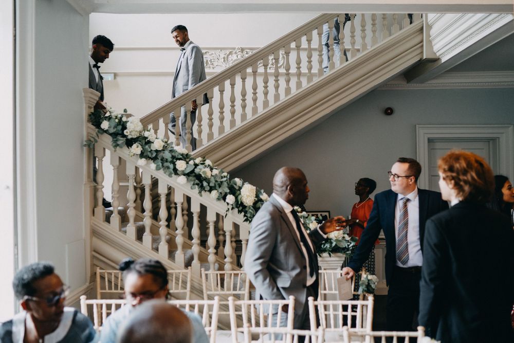 Interior of an elegant venue with a decorated staircase and guests mingling during an event.