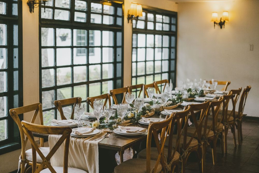 An elegant dining table set for a formal event with place settings near large windows in a restaurant.