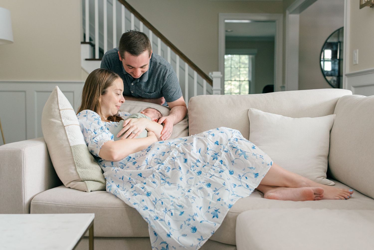 A new mother lays on the couch with her baby wrapped in a blanket in fair haven nj.