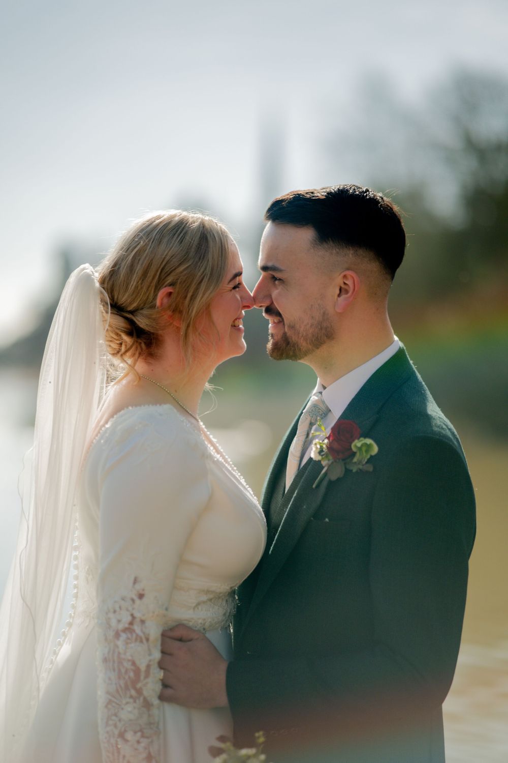 A romantic close-up moment between newlyweds outdoors in soft lighting.