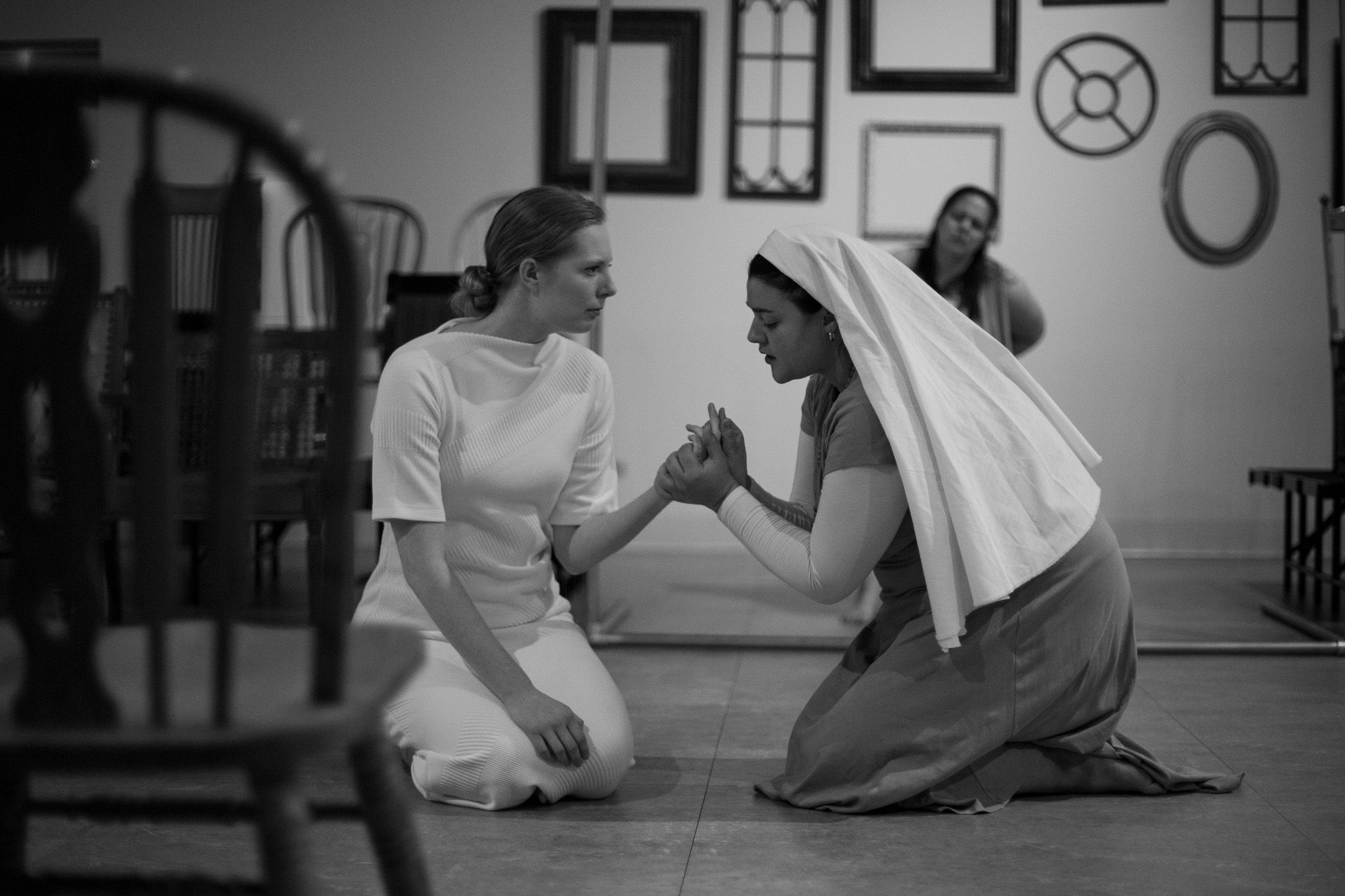 Black and white photo of two performers in theatrical costumes engaged in dramatic scene on stage floor.