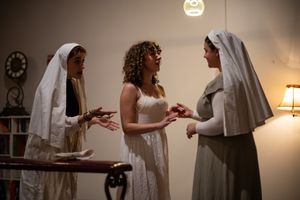 Three people in religious attire engaged in an animated discussion in a dimly lit room.