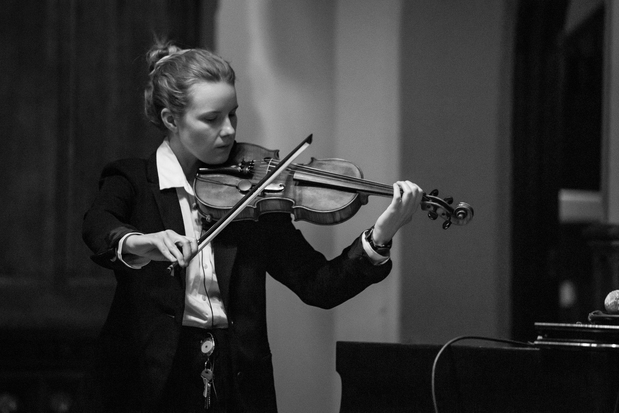 Professional violinist in formal attire performs classical music during an elegant black and white concert performance.