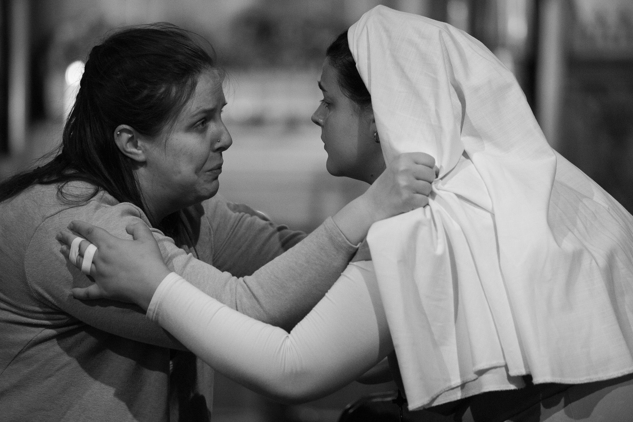 A dramatic black and white photograph shows an emotional interaction between two people, one wearing a nun's habit.