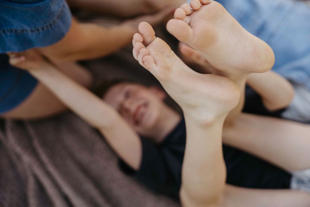 Close-up of bare feet in foreground with people relaxing on a bed in soft natural light.