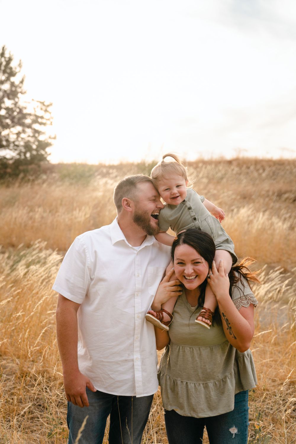 A loving family shares joyful laughter together in a golden wheat field at sunset.