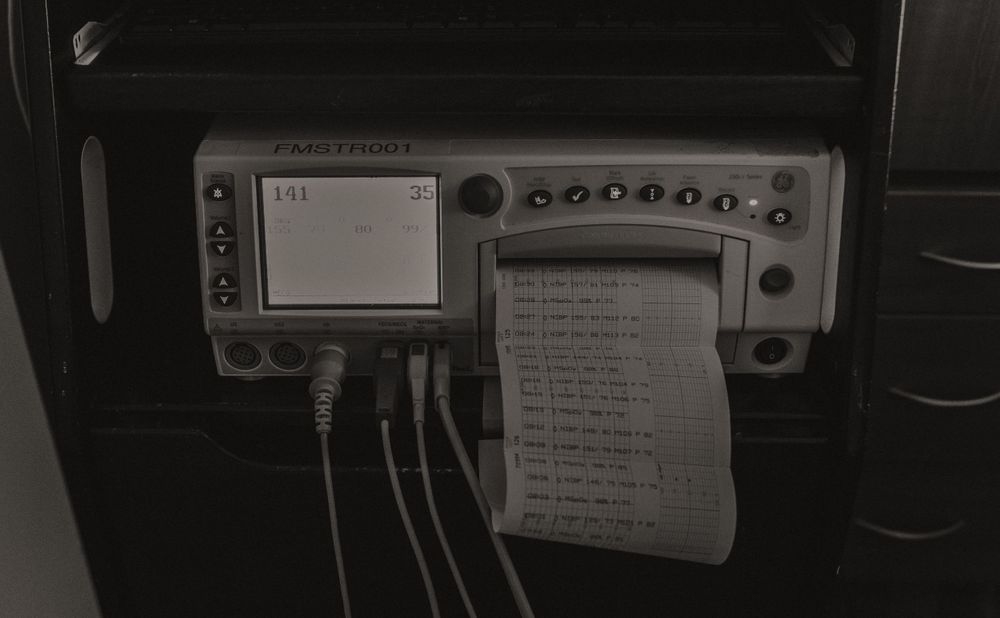 Medical monitoring equipment and devices in a hospital room shown in black and white.