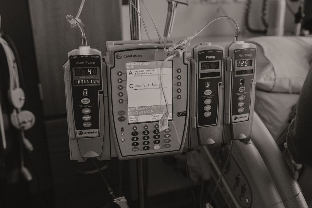Multiple medical monitoring devices and IV pumps mounted on a hospital wall.