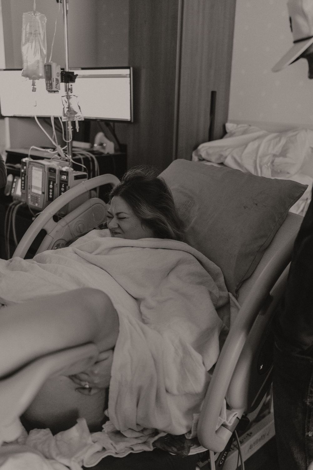 Patient lying in hospital bed with medical equipment and monitors in background.