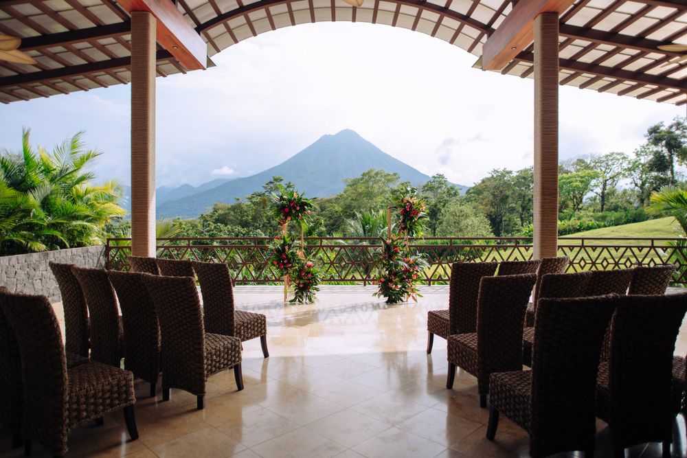 A covered terrace with wicker chairs overlooking a tropical mountain landscape at a luxury resort.