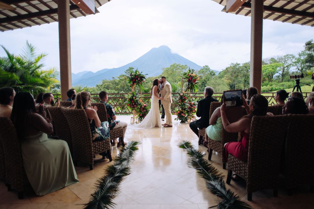 Wedding ceremony taking place under a covered pavilion with mountain views in the background.