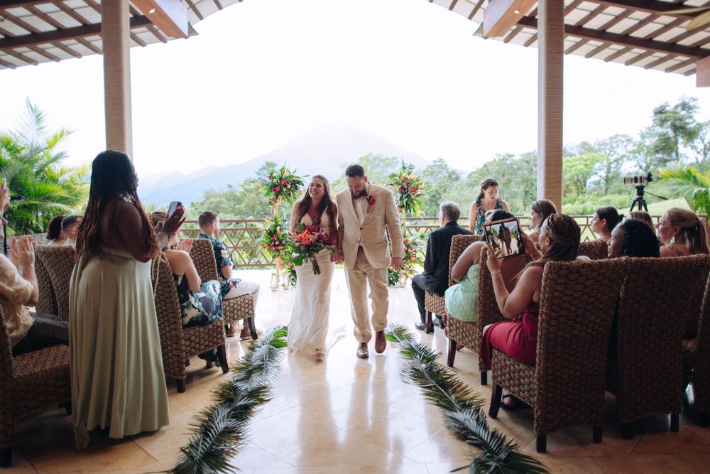 A wedding ceremony taking place on an open-air terrace with mountain views in a tropical setting.