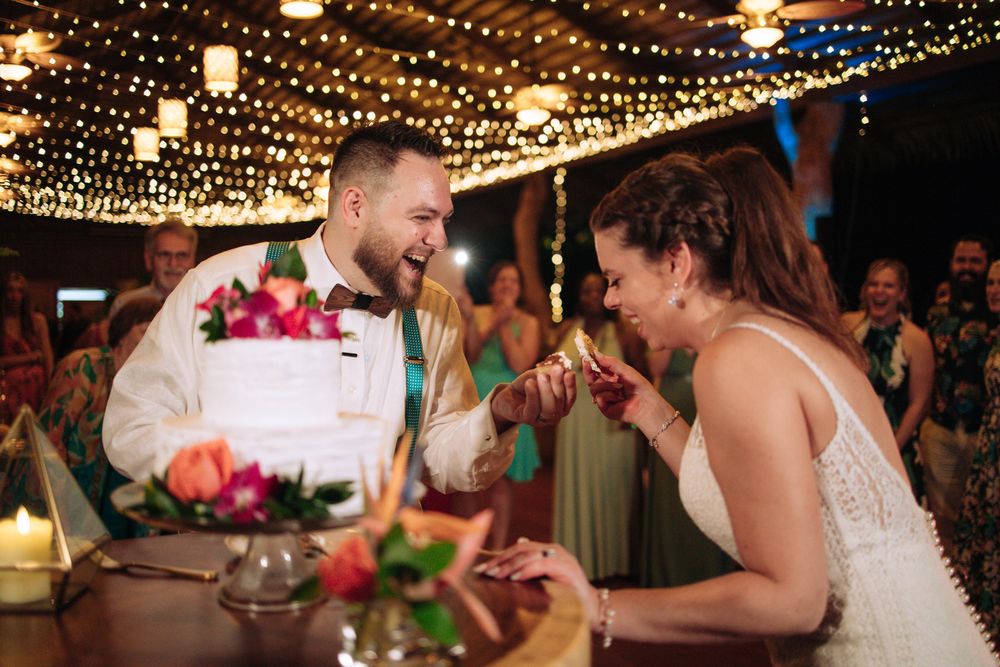 Joyful couple shares a candid moment during their reception while surrounded by twinkling lights and floral decorations.
