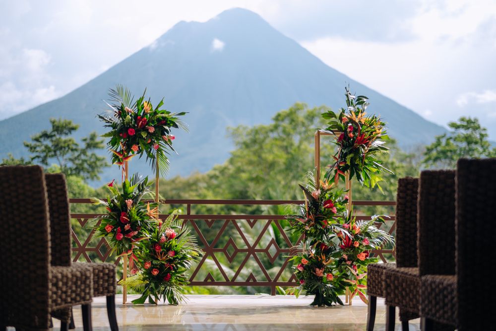 Floral decorations frame outdoor seating with a majestic volcano view in Costa Rica's natural landscape.