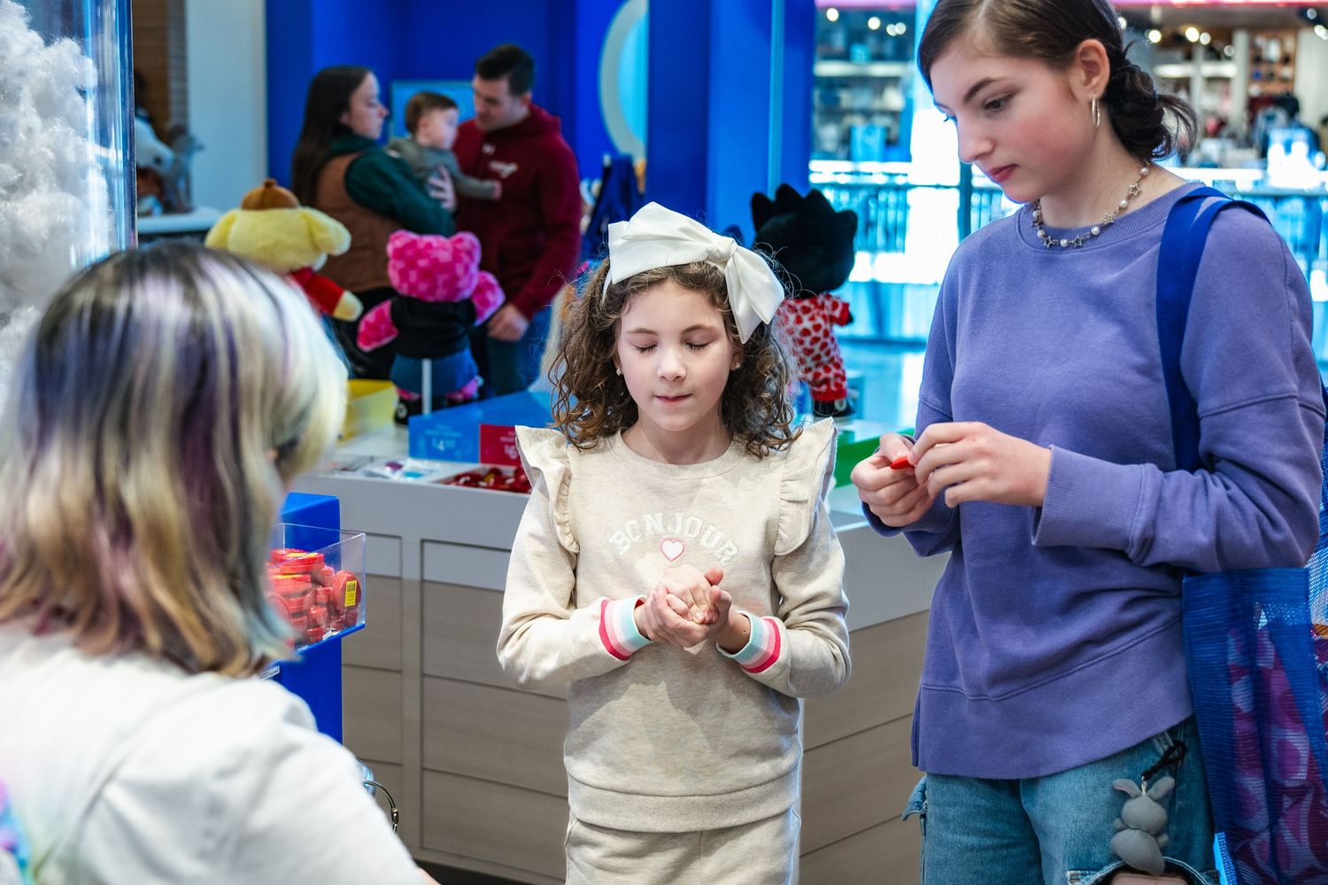 Children and adults participate in a hands-on learning activity inside a bright blue-walled educational space.