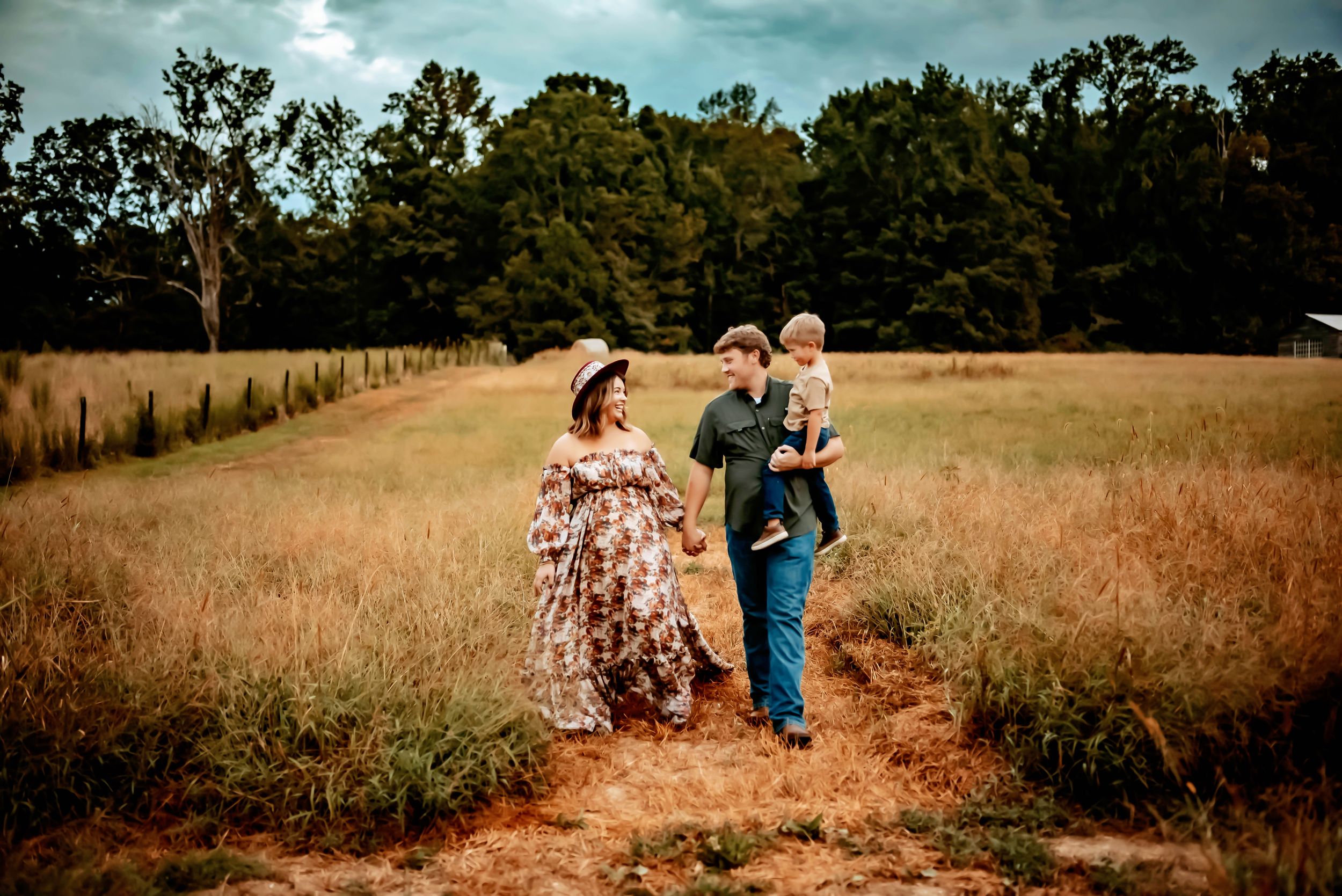 People walk together through a golden field on a dirt path surrounded by trees on a sunny afternoon. PROSPECT FARMS