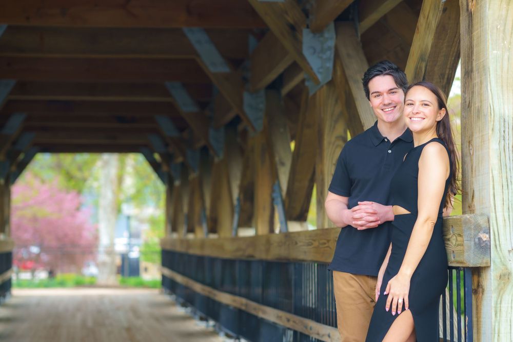 A couple shares a romantic moment under a covered wooden bridge walkway.