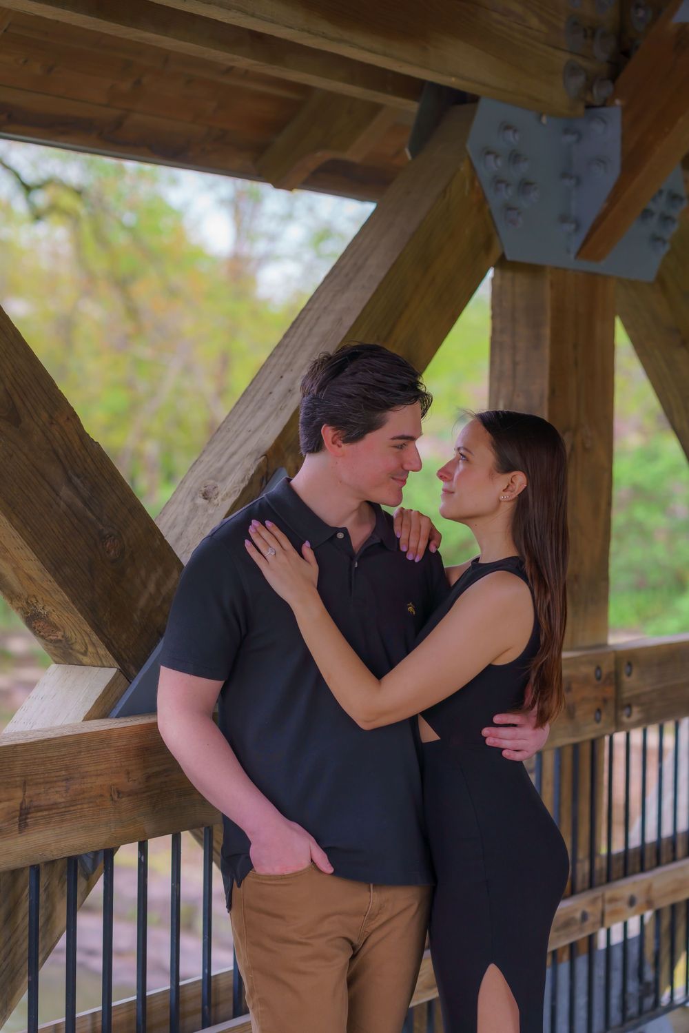 A couple shares an intimate moment in a rustic wooden gazebo.