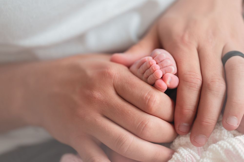 A sequence of hands tenderly holding and touching each other against a soft white background.