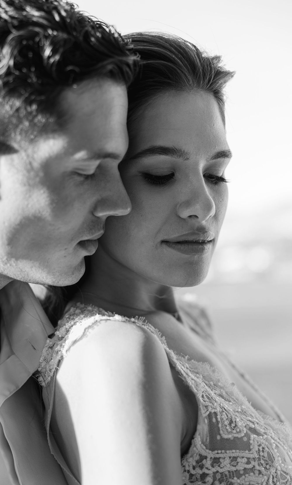 Intimate black and white portrait of newlyweds in a tender moment wearing wedding attire.