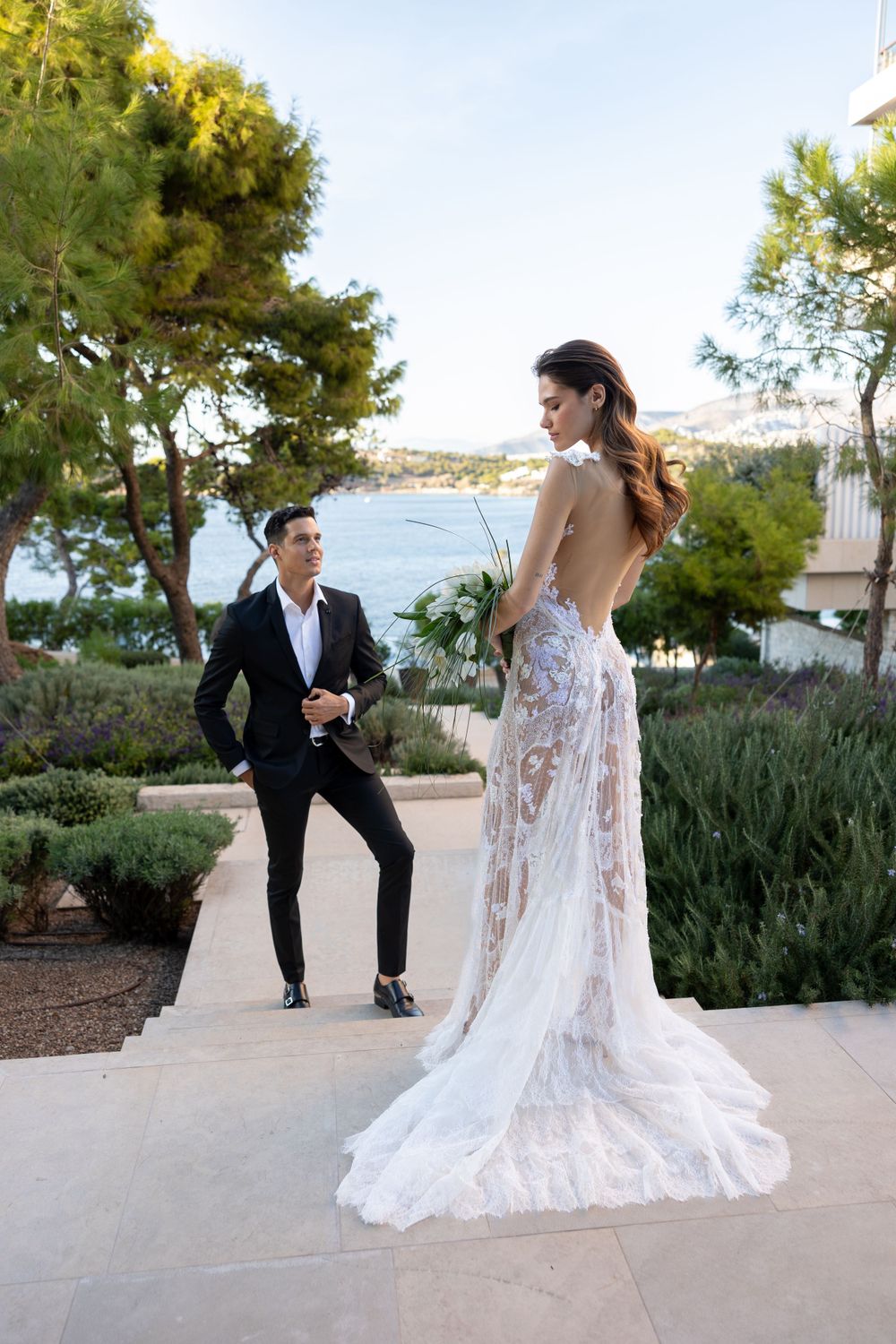 A romantic wedding moment captured outdoors with a stunning lace gown and scenic coastal view in the background.