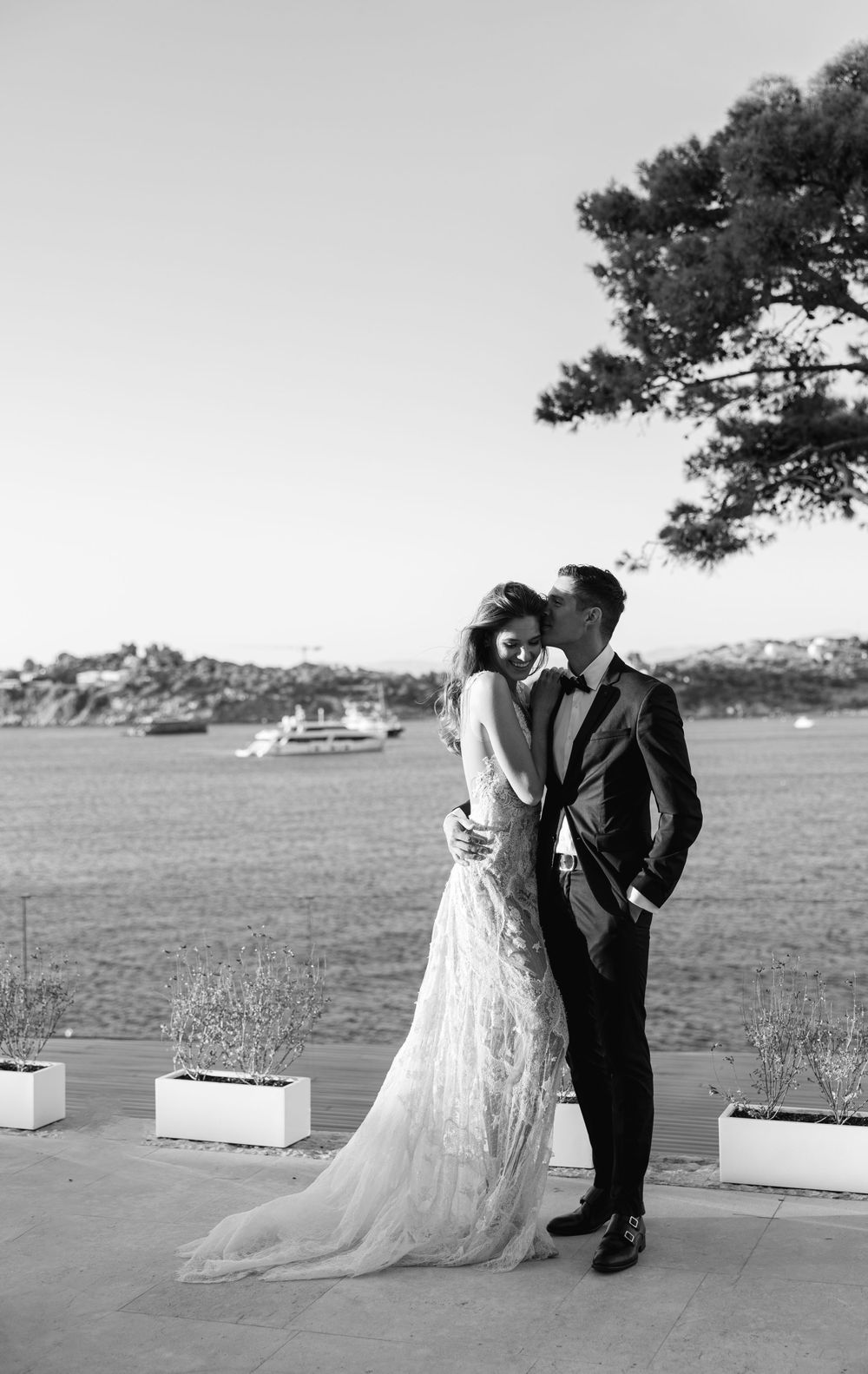 Black and white portrait of newlyweds against coastal backdrop.