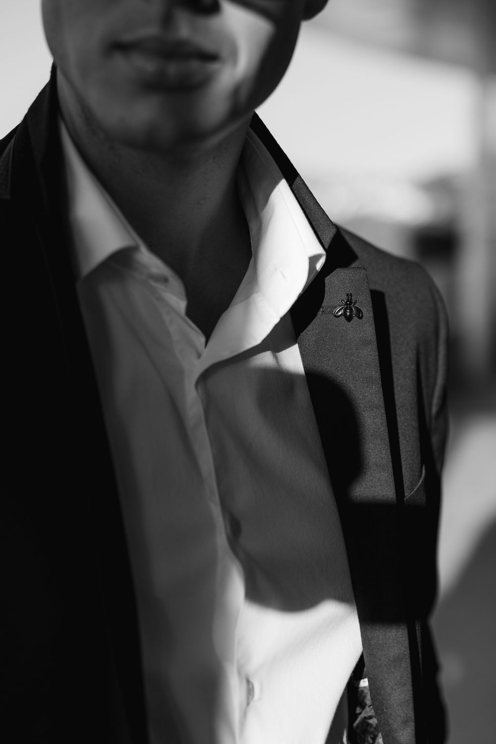 A black and white close-up shot showing a white dress shirt collar and dark jacket with soft selective focus.