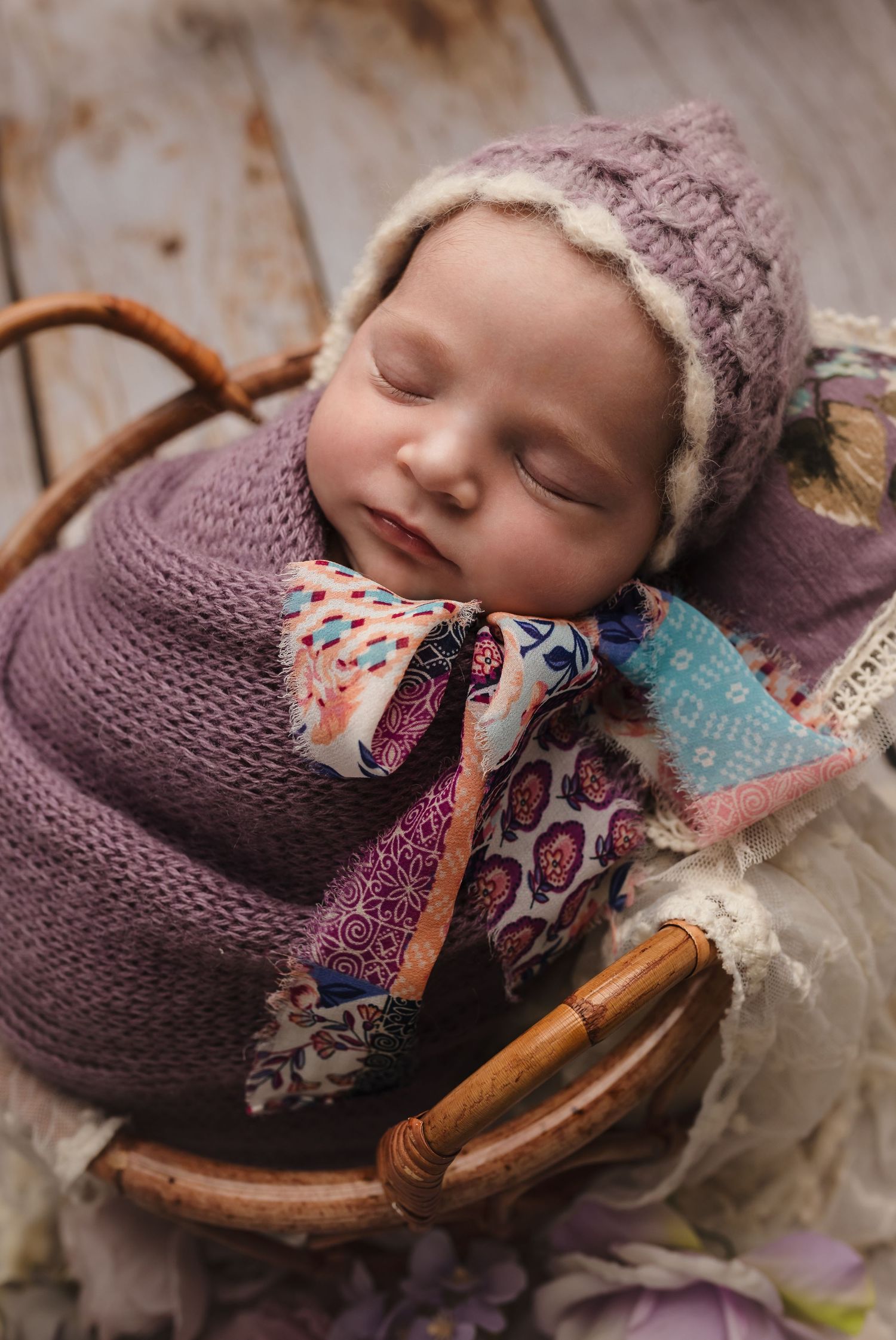 Charlottesville photographer, newborn girl in purple wrap and hat, sleeping in an a boho basket and on a purple pillow