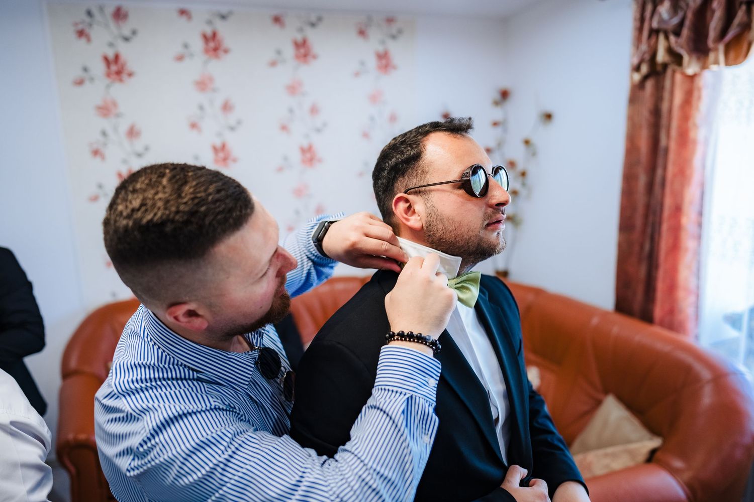 Men in formal attire sharing drinks and conversation at wedding celebration.