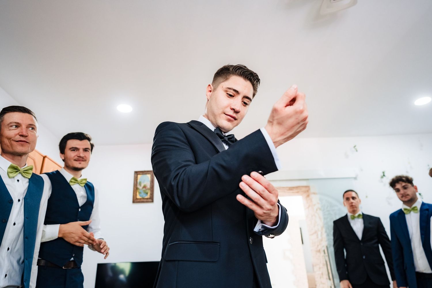 Wedding party members raising glasses in celebration against white walls.
