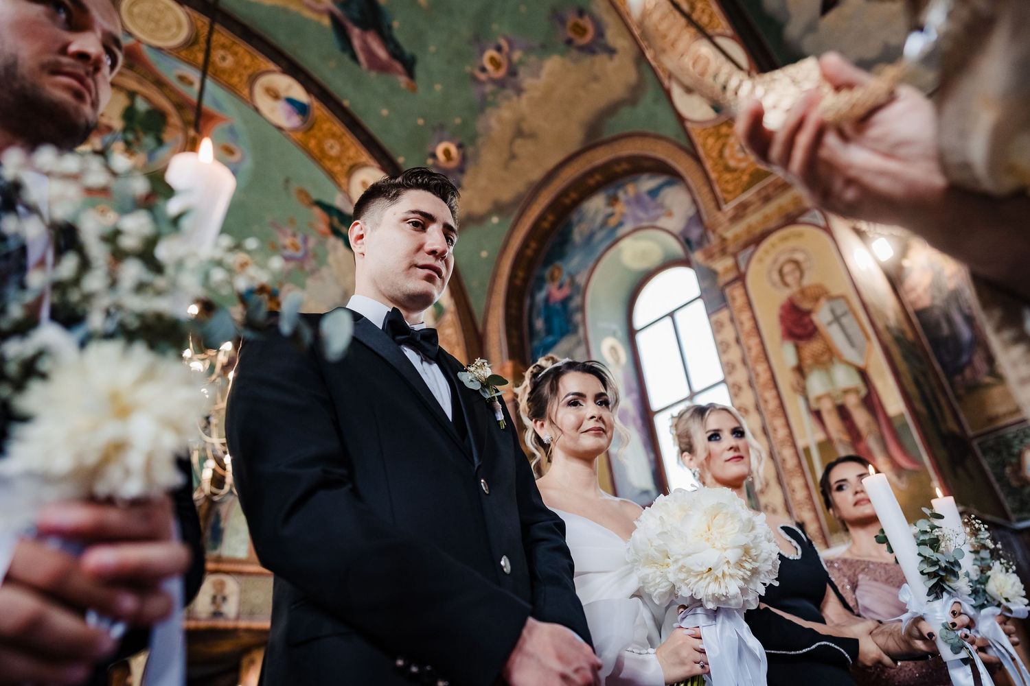 Orthodox wedding ceremony with crowning ritual in progress at decorated church altar.