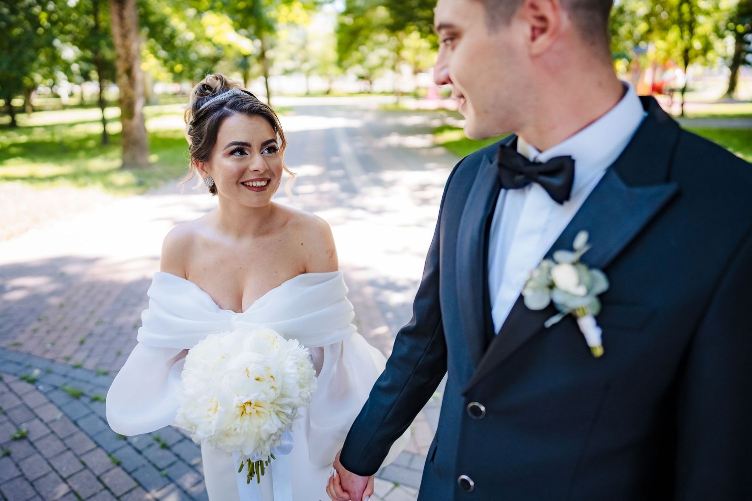 Elegant wedding portraits with white bouquet against natural outdoor backdrop.