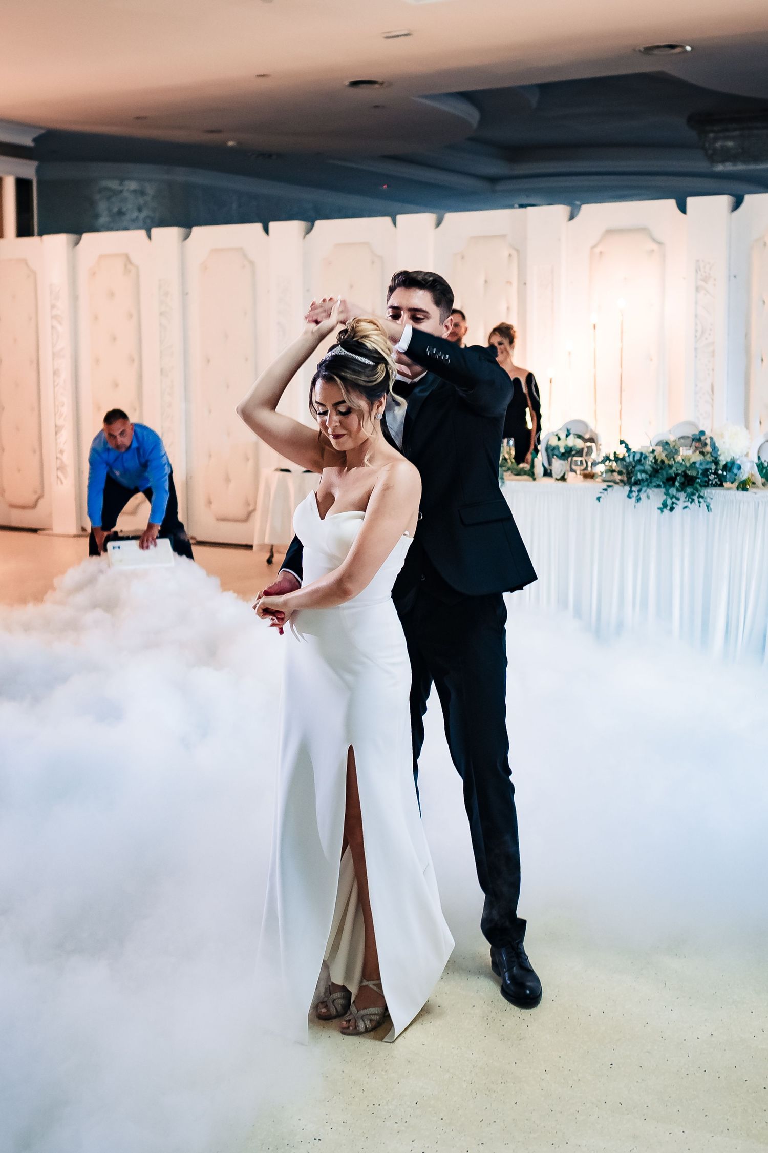 Couple dancing on a misty dance floor with dramatic lighting effects at their wedding reception.