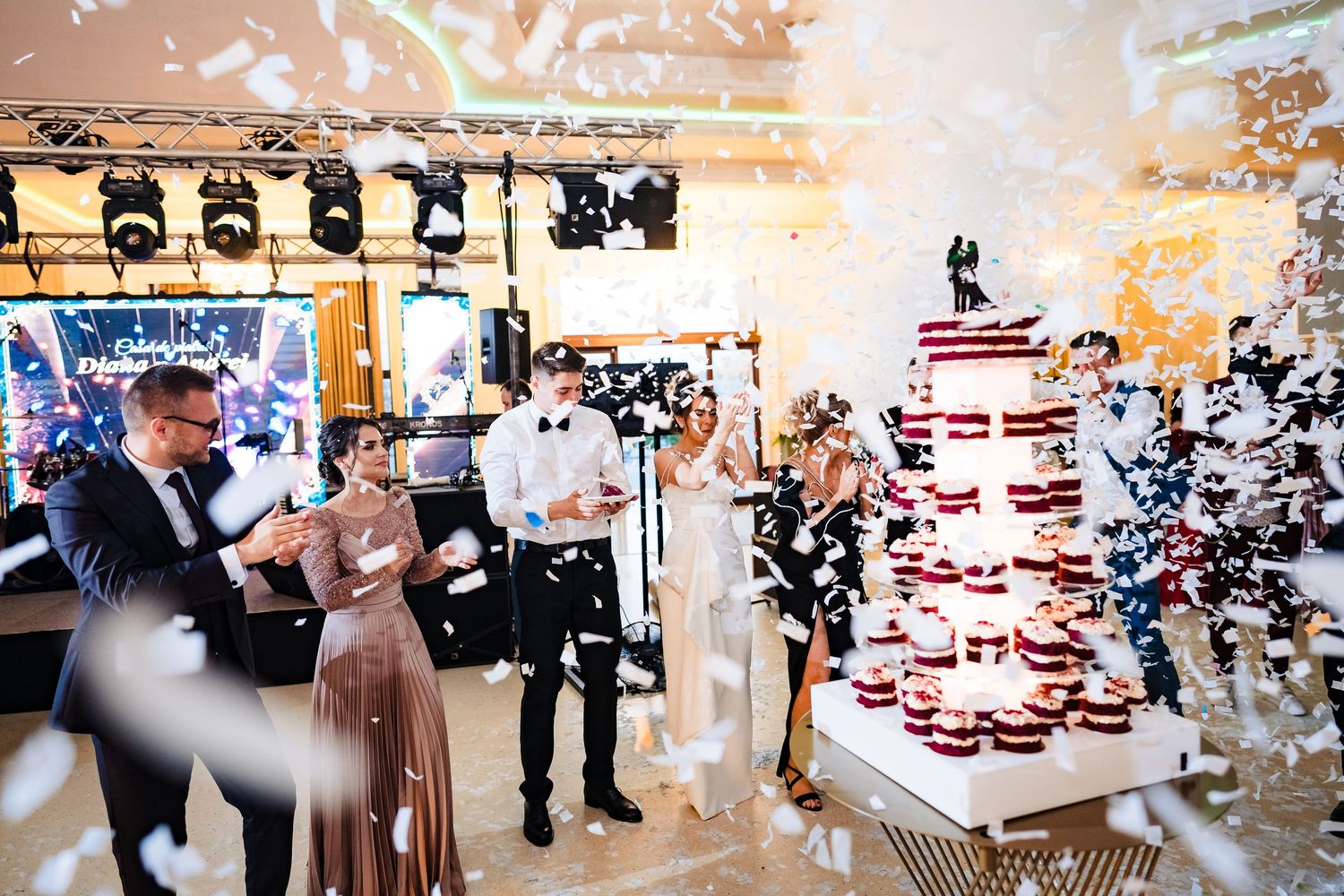 Wedding cake being presented with confetti and sparklers in an elegant venue setting.