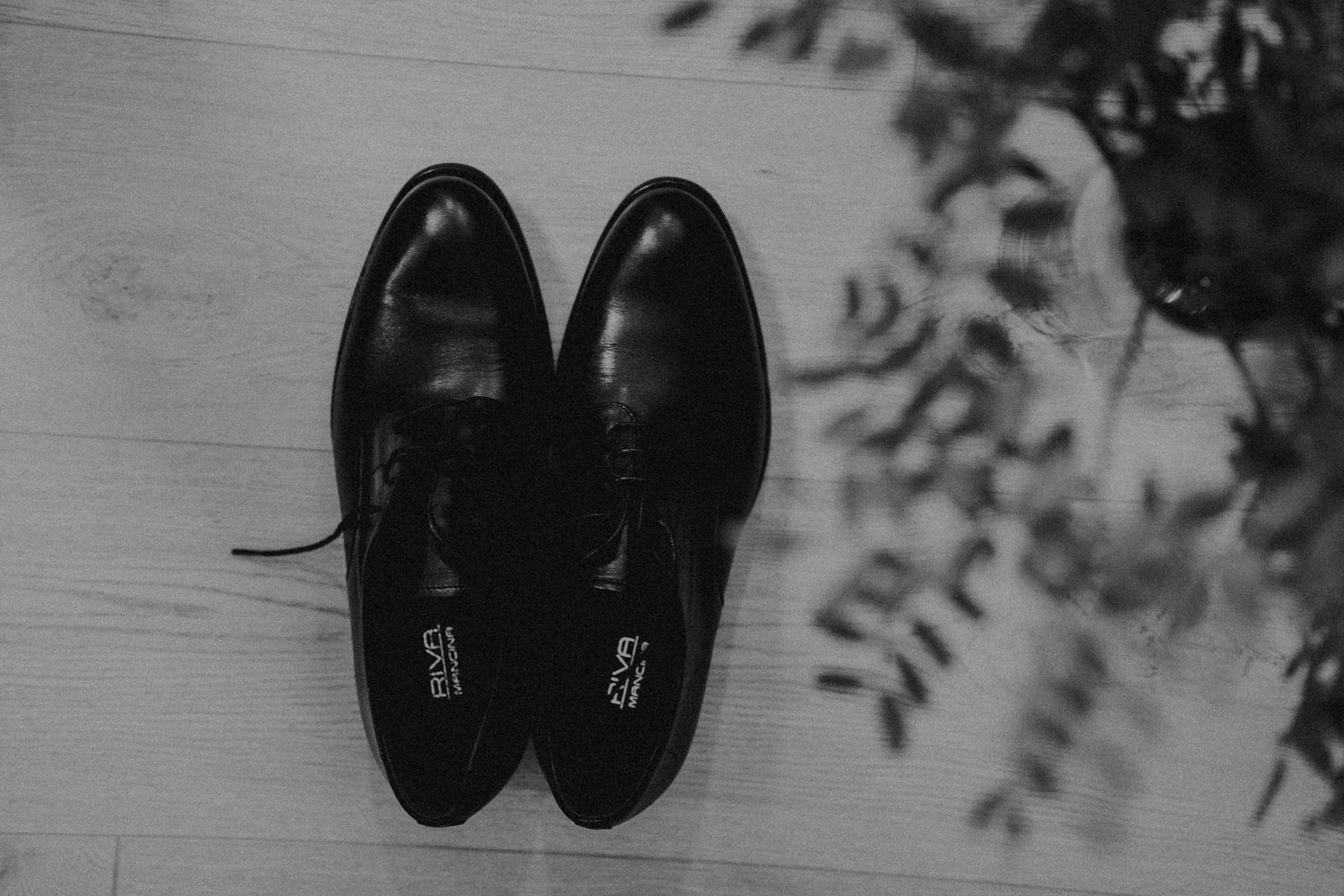 Black formal dress shoes arranged on dark wooden surface.
