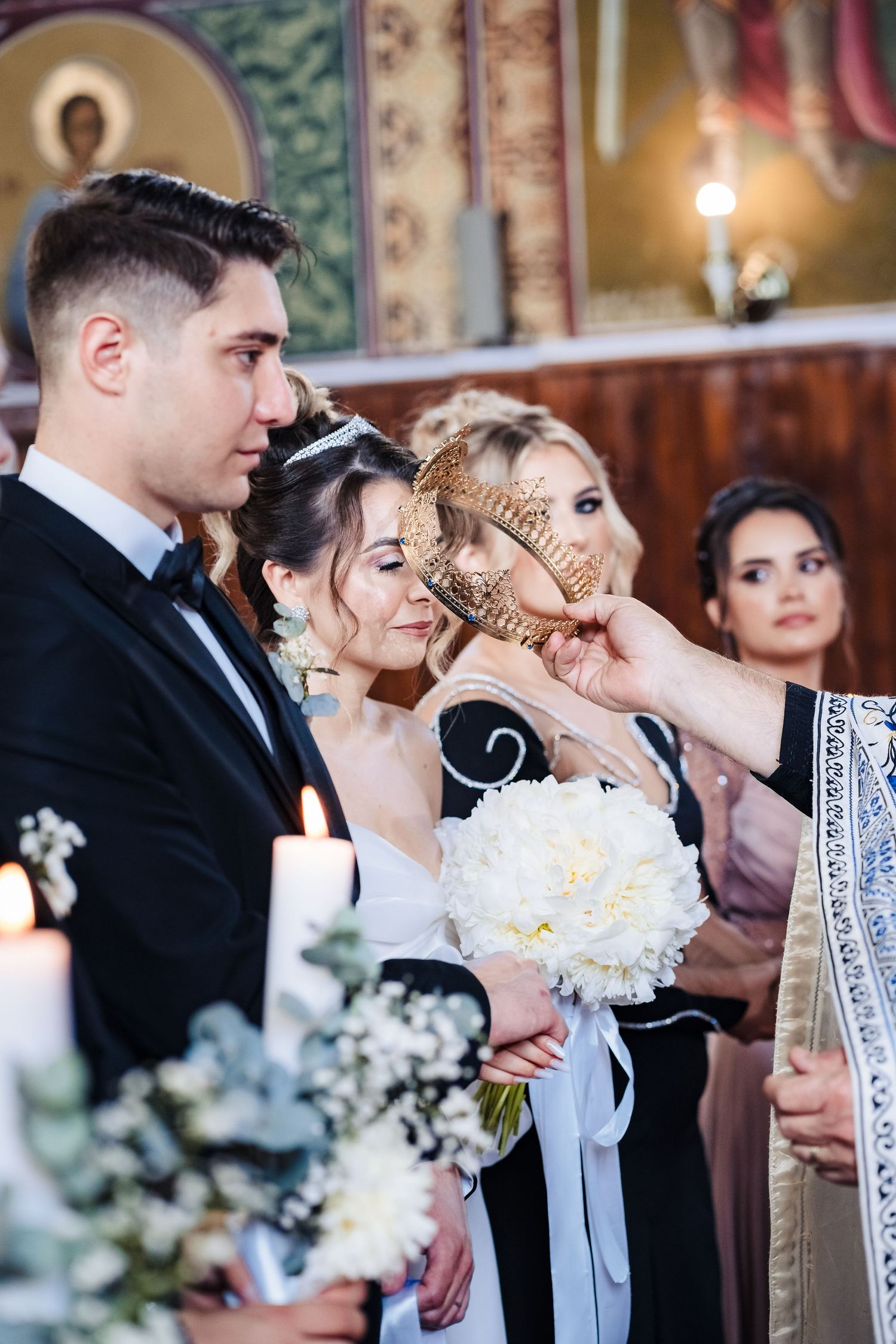Wedding party lineup with white floral bouquets in an ornately decorated church.